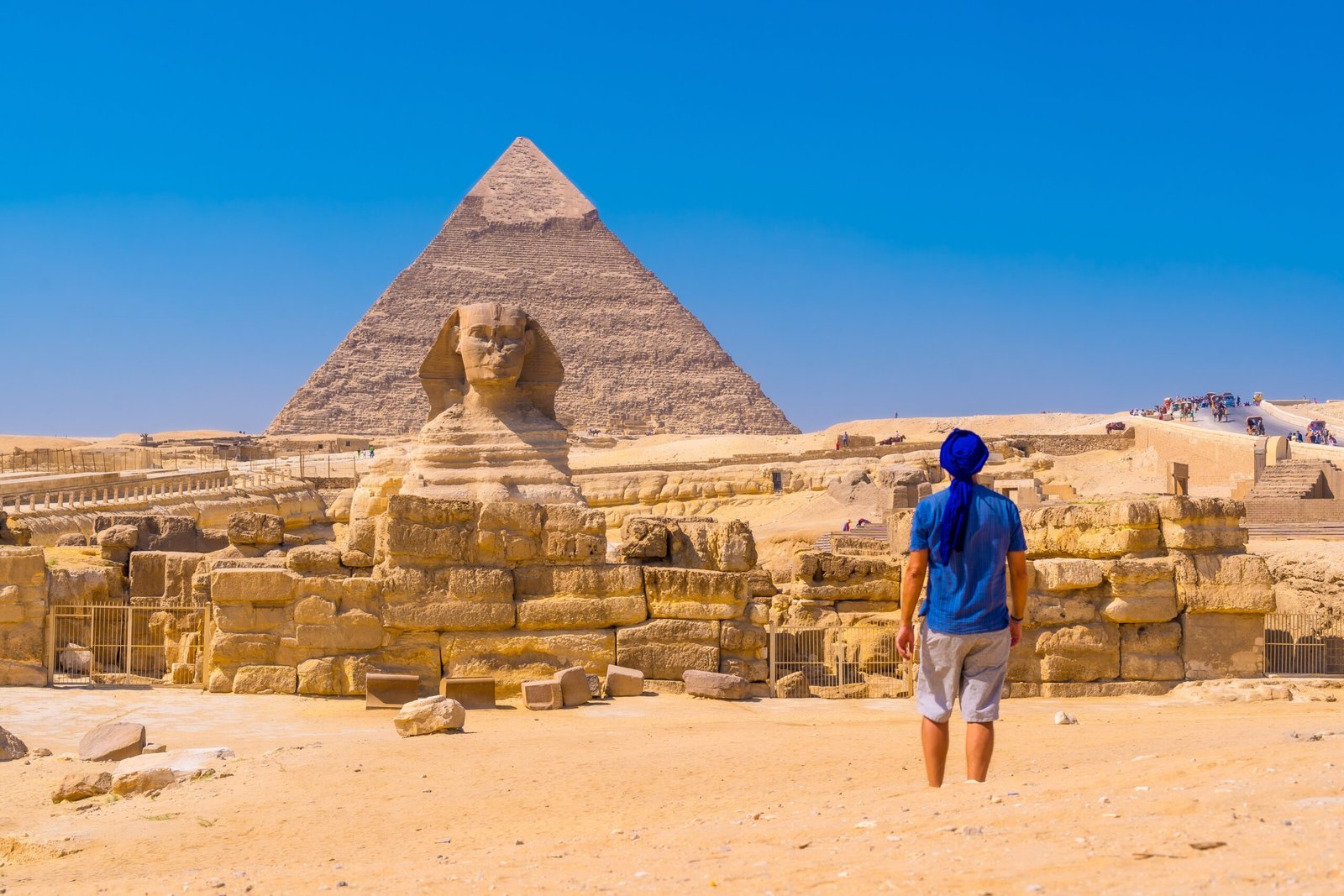 young man walking towards the great sphinx of giza and in the background the pyramid of khafre,